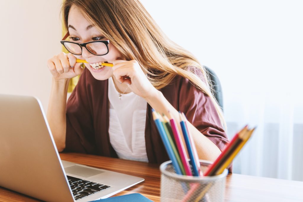 woman at laptop with pencil in mouth